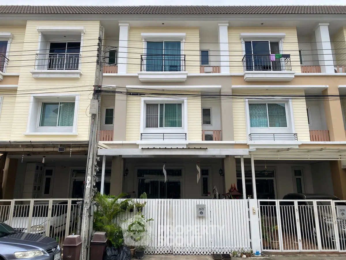 Charming three-story townhouse with balconies and gated entrance in a serene neighborhood.