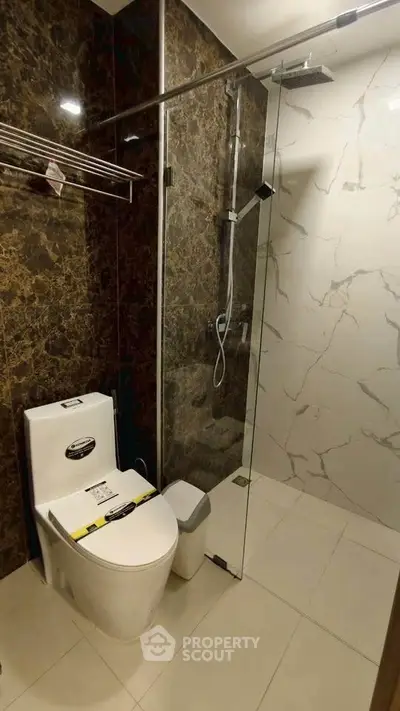 Modern bathroom with glass shower and marble walls in luxury apartment.