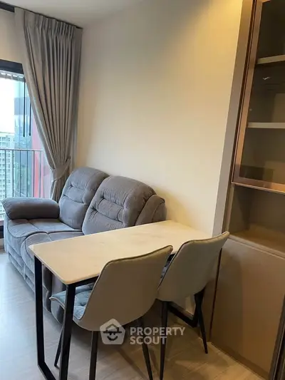 Cozy living room with modern sofa and dining table, featuring a city view from the balcony.