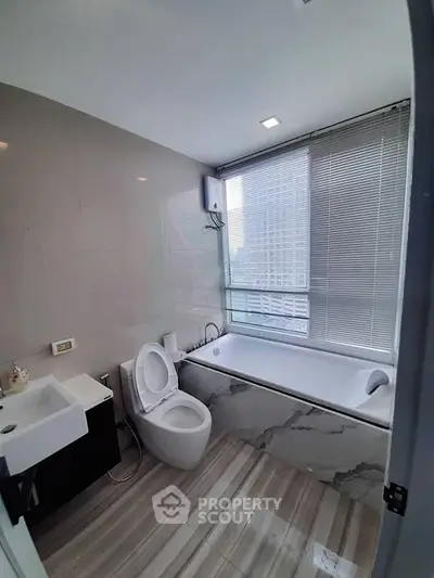 Modern bathroom with city view, featuring sleek fixtures and a luxurious bathtub.
