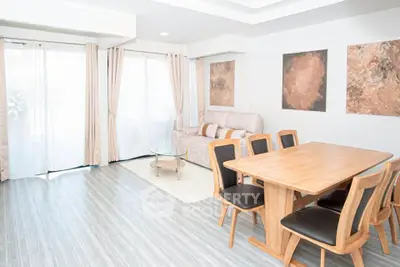 Spacious living room with modern decor and natural light, featuring a cozy sofa and elegant dining area.