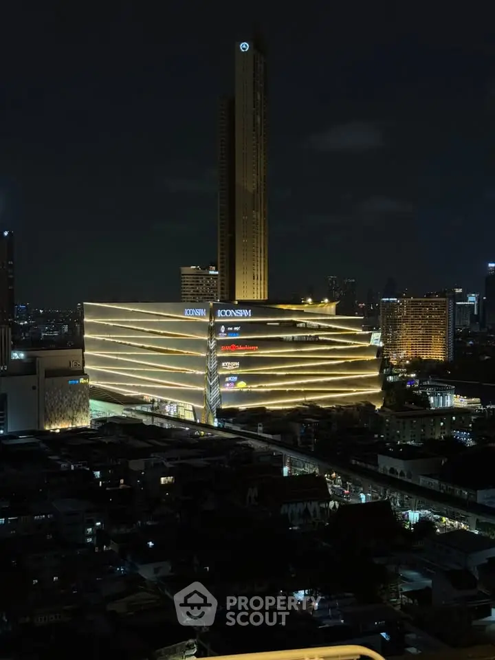 Stunning night view of a modern high-rise building with illuminated facade in a bustling cityscape.