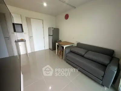Modern living room with sleek gray sofa and compact dining area in minimalist apartment.