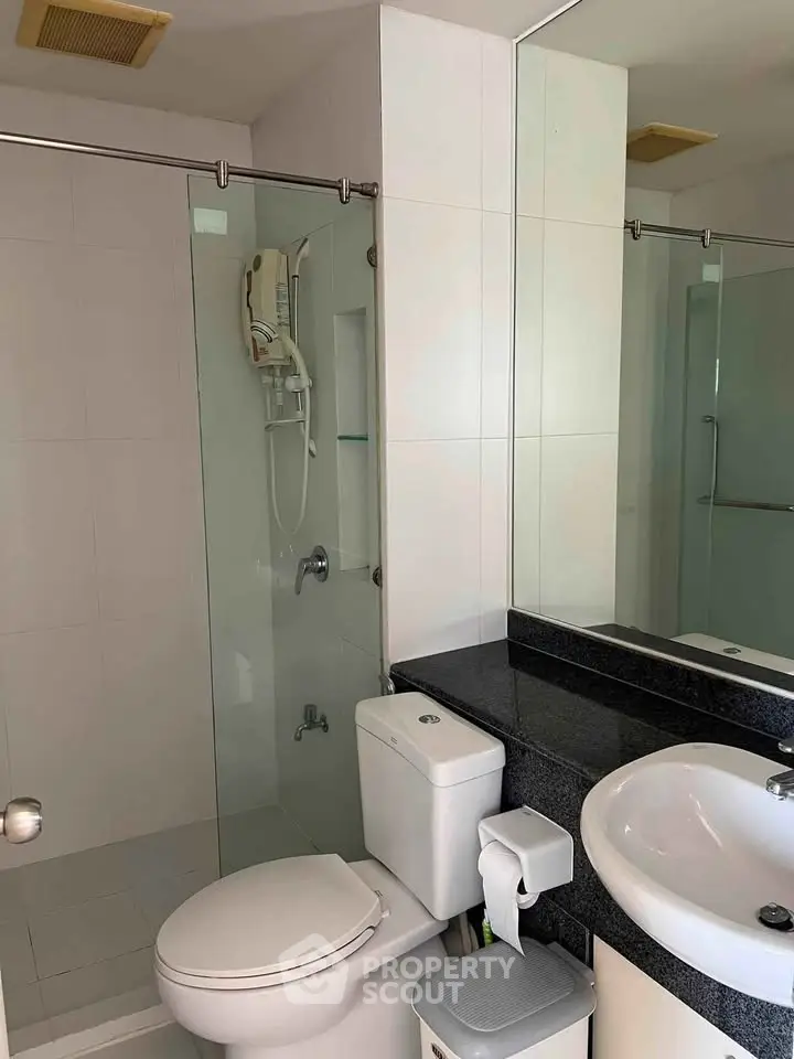 Modern bathroom with glass shower and sleek fixtures in a contemporary apartment.