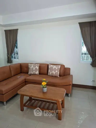 Cozy living room with brown leather sectional sofa and wooden coffee table, perfect for relaxation.