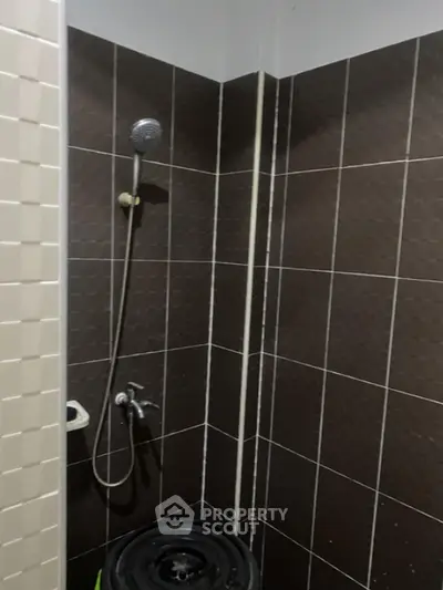 Compact bathroom with modern tiled shower area and dark brown tiles.