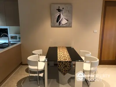 Modern dining area with elegant table and chairs, adjacent to a sleek kitchen space.