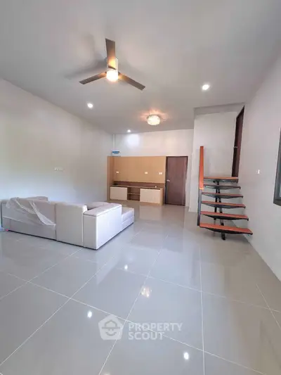 Spacious modern living room with sleek staircase and ceiling fan
