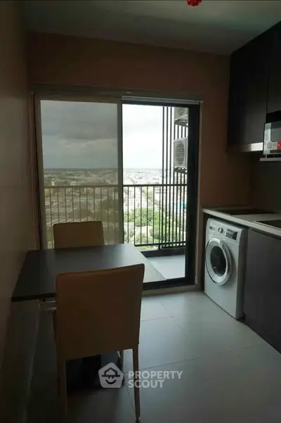 Modern kitchen with balcony view, featuring sleek appliances and dining area.