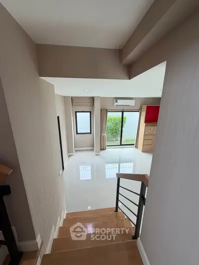 Spacious modern living room with large windows and sleek staircase, perfect for natural light lovers.