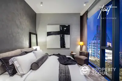 Luxurious bedroom with plush bedding, modern decor, and stunning city views through floor-to-ceiling windows, offering an urban oasis in a prime location.