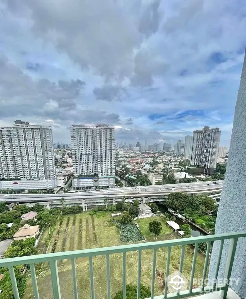 Stunning cityscape view from high-rise balcony with lush greenery and urban skyline.