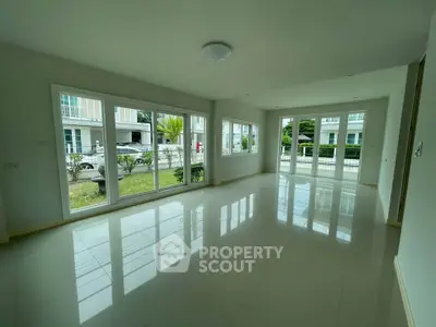 Spacious living room with large windows offering abundant natural light and garden views.