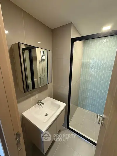 Modern bathroom with sleek shower and stylish vanity in contemporary apartment.