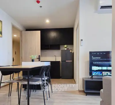 Modern open-layout living room with dining area and kitchen, featuring sleek furniture and a smart TV.