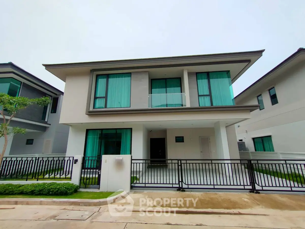 Modern two-story house with sleek design and large windows in a suburban neighborhood.