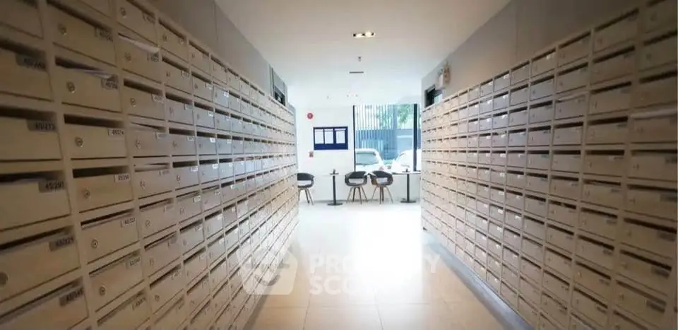 Modern apartment building mailroom with rows of mailboxes and seating area.