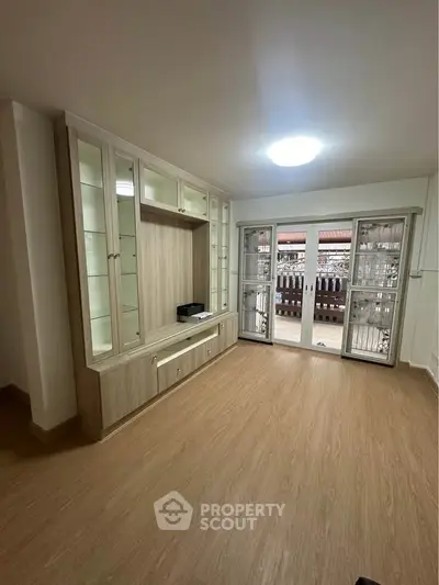 Spacious living room with built-in wooden cabinets and large windows for natural light.