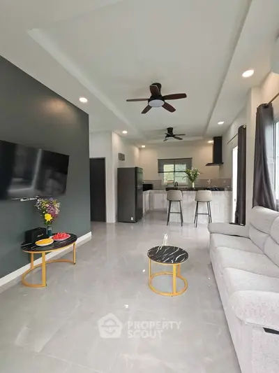 Modern living room with open kitchen, stylish decor, and ceiling fans in a contemporary home.