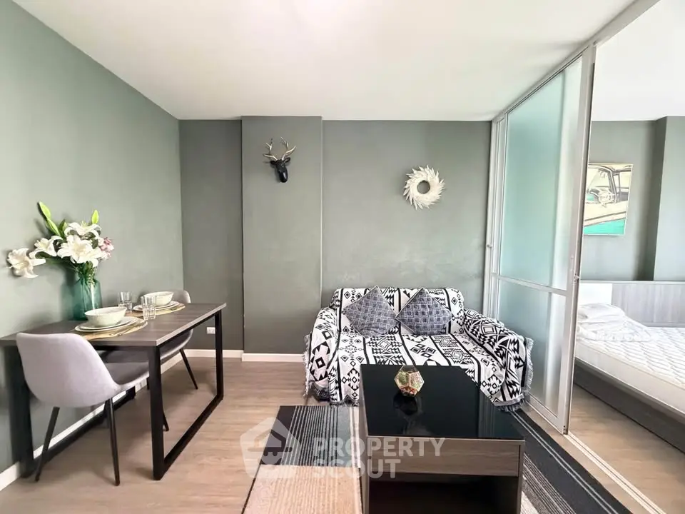 Modern living room with stylish decor and adjacent bedroom in open layout apartment.