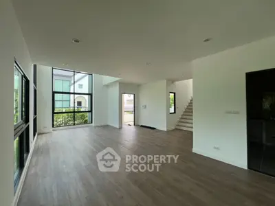 Spacious modern living room with large windows and wooden flooring in a luxury home.