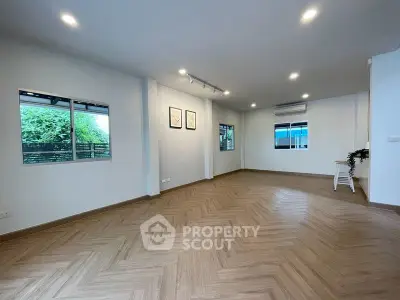 Spacious modern living room with herringbone wood flooring and large windows.