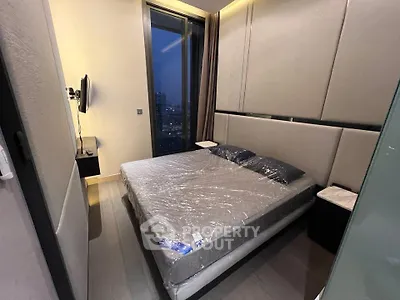 Modern bedroom with large window and sleek design in high-rise apartment.