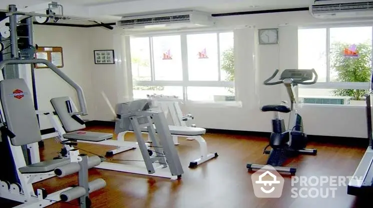 Modern gym with exercise equipment and large windows in a residential building.