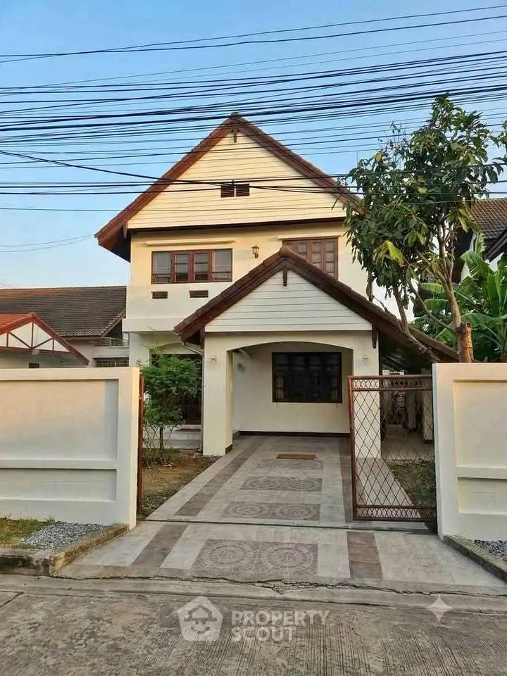 Charming two-story house with gated driveway and lush greenery, perfect for family living.