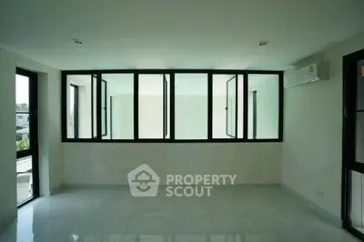 Spacious modern room with large windows and air conditioning, perfect for natural light and comfort.