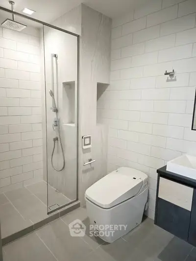 Modern bathroom with sleek shower and high-tech toilet in minimalist design.