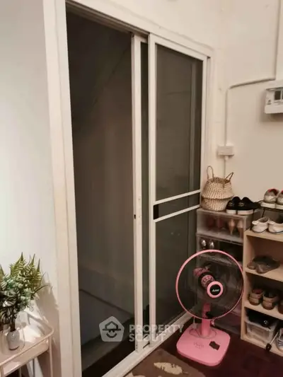 Cozy interior with sliding glass door and shoe rack, perfect for compact living spaces.