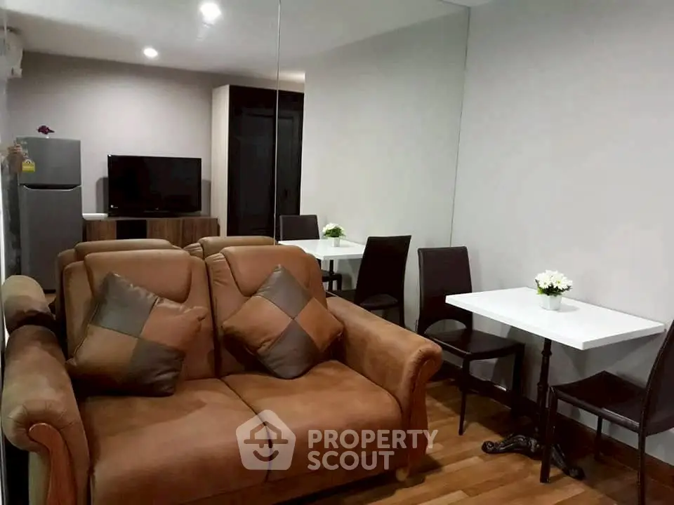 Cozy living room with brown leather sofa and dining area in modern apartment.