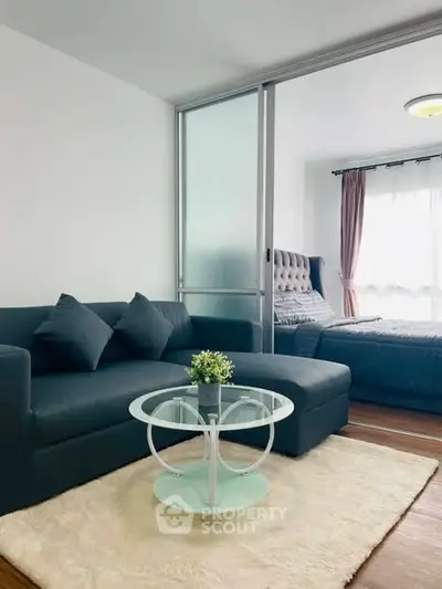 Modern studio apartment with cozy living area and stylish bedroom separated by sliding glass doors.