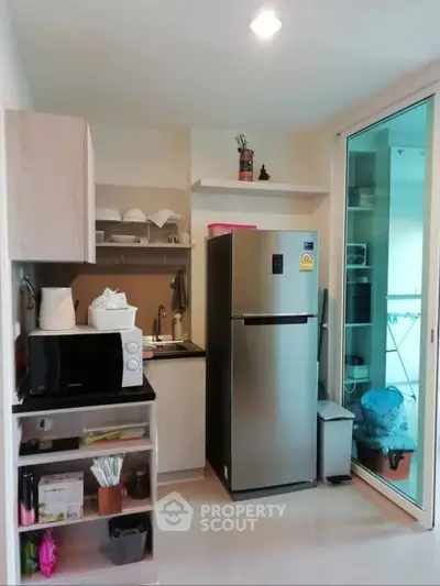 Modern kitchen with stainless steel fridge and microwave in compact apartment