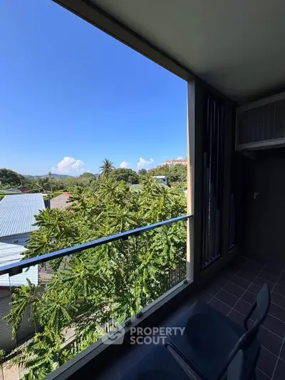 Spacious balcony with stunning green views and clear blue sky, perfect for relaxation.