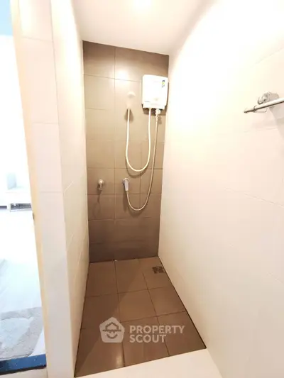 Modern minimalist bathroom with tiled shower area and water heater.