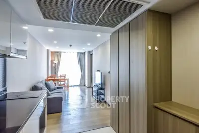 Modern living room with wooden flooring and natural light, featuring a cozy sofa and dining area.