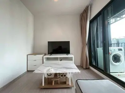 Modern living room with TV, sleek furniture, and balcony view with washing machine.