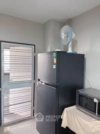 Modern kitchen with sleek black fridge and microwave, featuring a compact fan for added convenience.