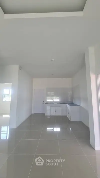 Spacious modern kitchen with sleek tile flooring and ample natural light.