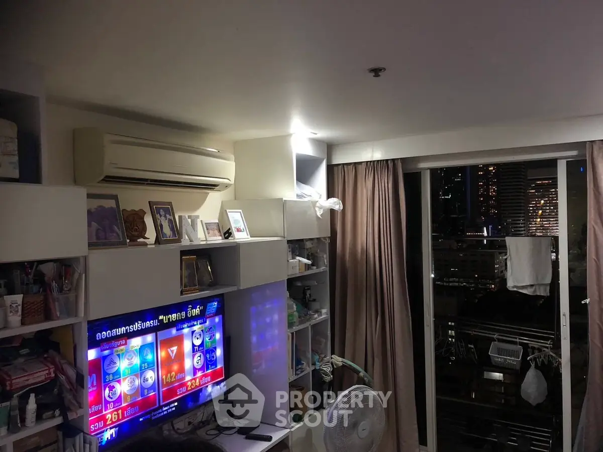 Cozy living room with city view, modern shelving, and air conditioning in urban apartment.