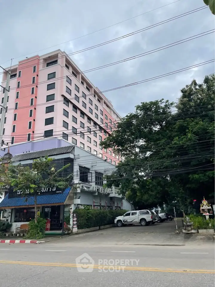 Modern pink apartment building with lush greenery and street view