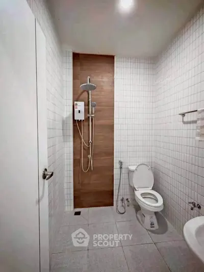 Modern bathroom with sleek shower and white tiled walls in a contemporary home.