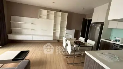 Modern open-plan living room and kitchen with sleek furniture and wooden flooring.