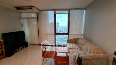 Cozy living room with city view, featuring a comfortable sofa and modern entertainment setup.
