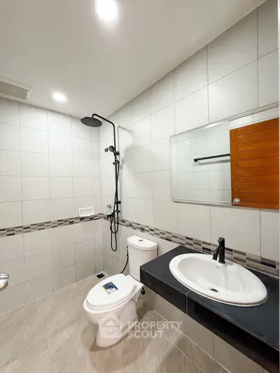 Modern bathroom with sleek fixtures and elegant tile design, featuring a spacious shower area and contemporary sink.