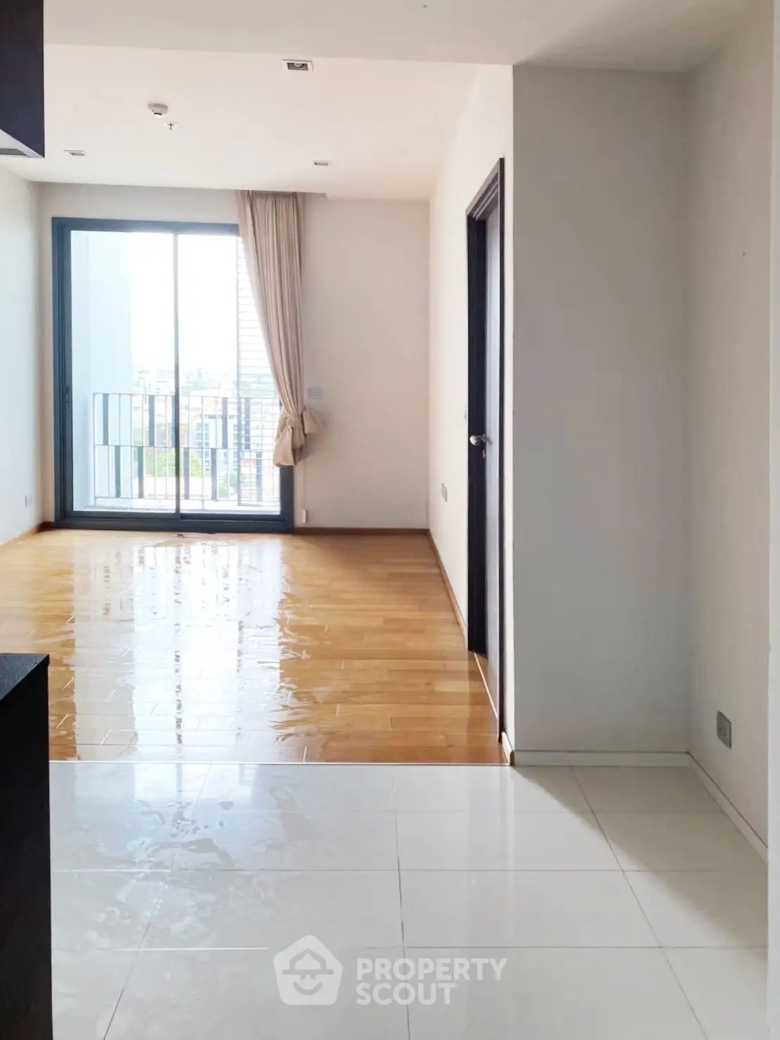 Spacious apartment with wooden flooring and large windows offering city views.