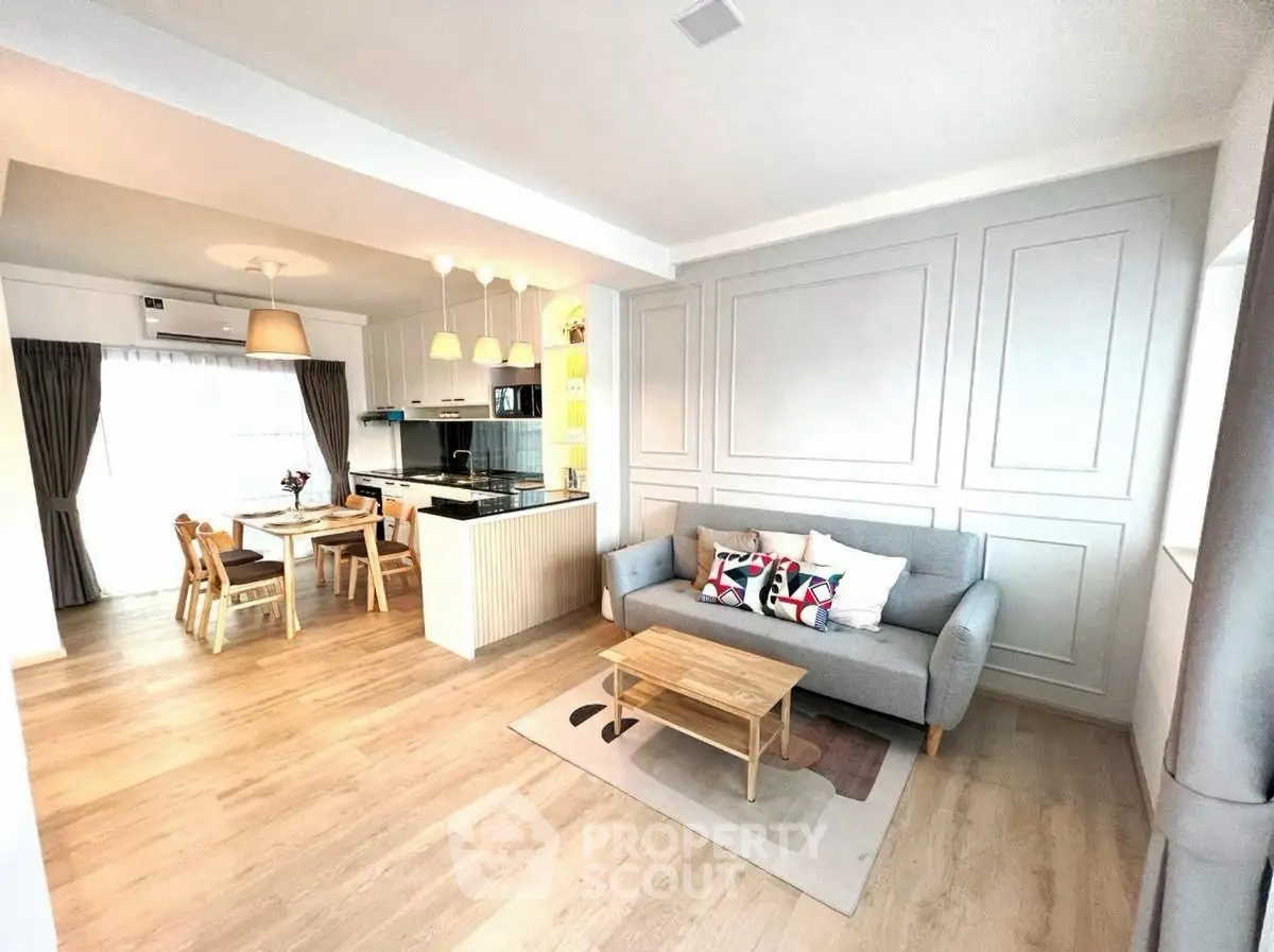 Modern open-plan living room with stylish kitchen and dining area, featuring elegant decor and ample natural light.