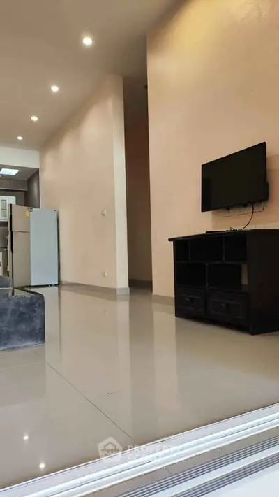 Modern living room with sleek TV setup and open kitchen view, perfect for contemporary living.